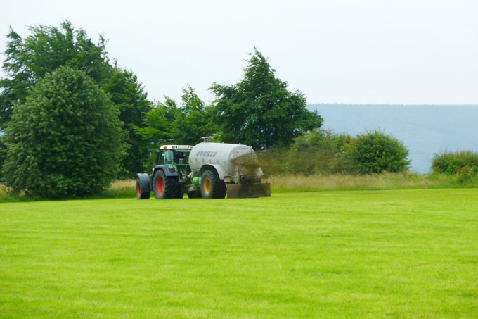 Traktor verteilt Gülle auf einer Wiese - Foto: C. Mayr